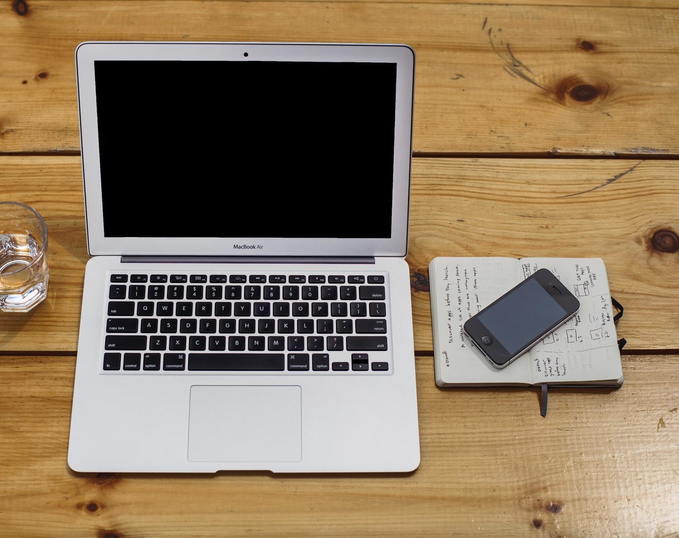 MacBook Air beside black iPhone 4 and drinking glass